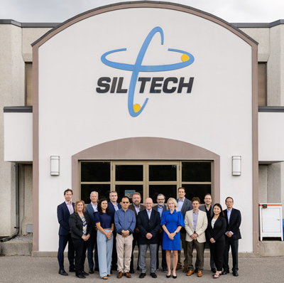 Siltech Personal Care Products team poses in front of Siltech office, with large Siltech logo overhead